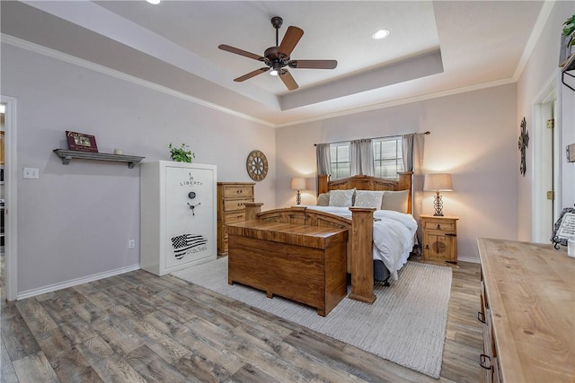 bedroom featuring a tray ceiling, ceiling fan, wood-type flooring, and ornamental molding