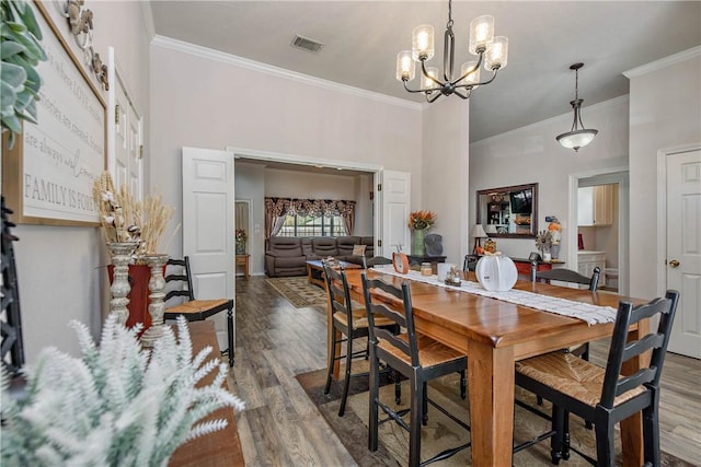 dining area featuring an inviting chandelier, wood-type flooring, a high ceiling, and ornamental molding