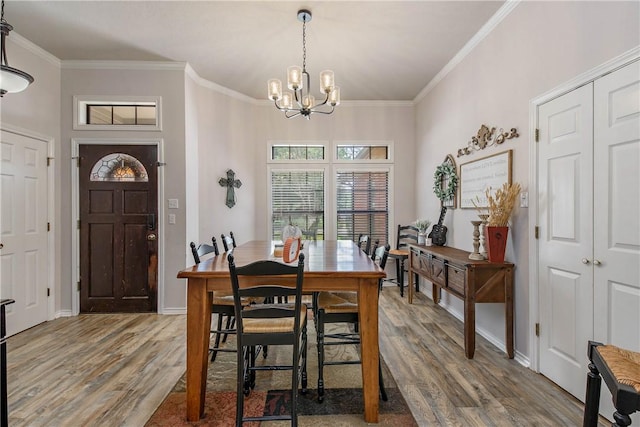 dining space featuring a chandelier, wood-type flooring, and crown molding