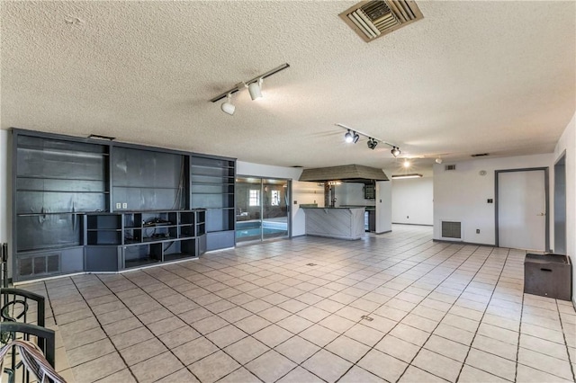 180 Fcr 797, Donie, TX 75838 - unfurnished living room featuring rail lighting, tile patterned floors, a textured ceiling, and baseboards