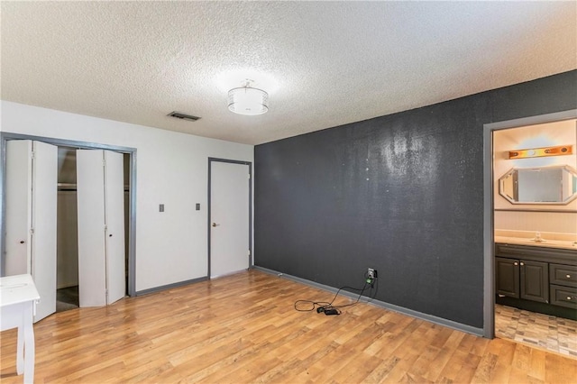 180 Fcr 797, Donie, TX 75838 - unfurnished bedroom with light wood-style floors, a sink, a textured ceiling, and connected bathroom