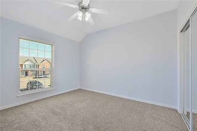 empty room featuring ceiling fan, lofted ceiling, and carpet flooring