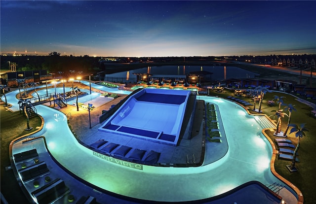 pool at dusk featuring a water slide