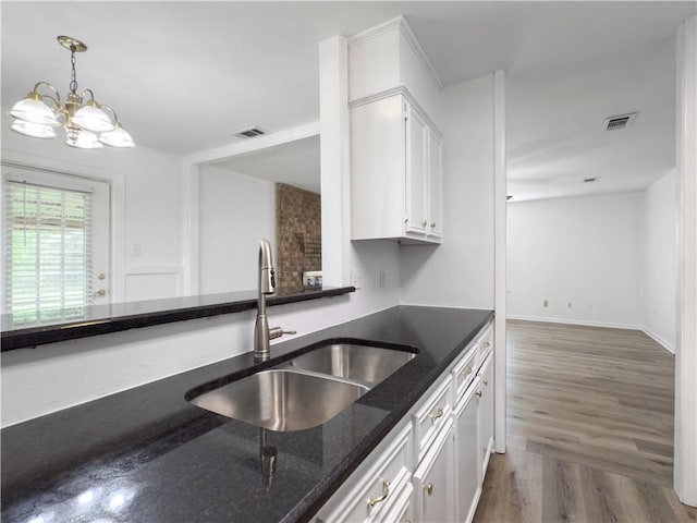 3234 Red Robin Loop, Bryan, TX 77802 - kitchen with white cabinets, dark stone counters, pendant lighting, wood finished floors, and a chandelier