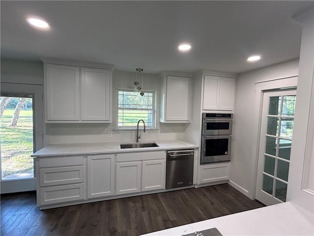 kitchen with white cabinets, stainless steel appliances, hanging light fixtures, and sink