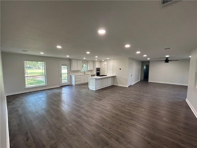 unfurnished living room with dark hardwood / wood-style flooring, ceiling fan, and sink