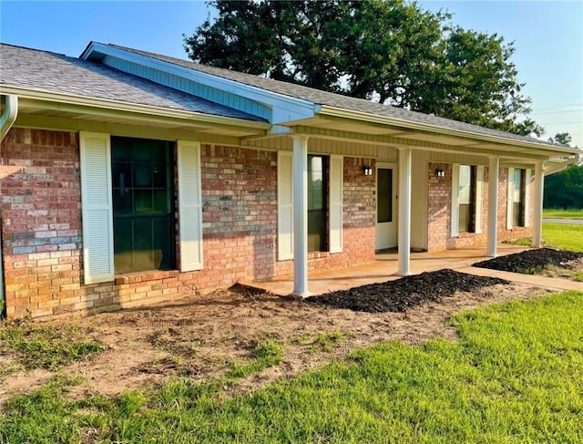 exterior space with a shingled roof and brick siding