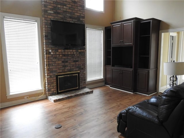 living room with a fireplace, a towering ceiling, and hardwood / wood-style flooring