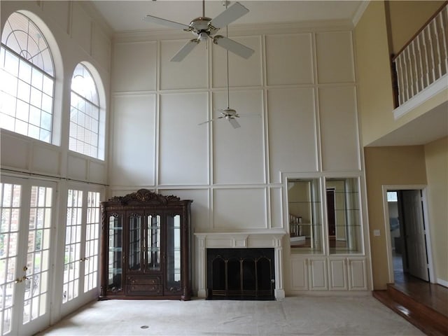 unfurnished living room with ceiling fan, french doors, a high ceiling, light hardwood / wood-style flooring, and crown molding