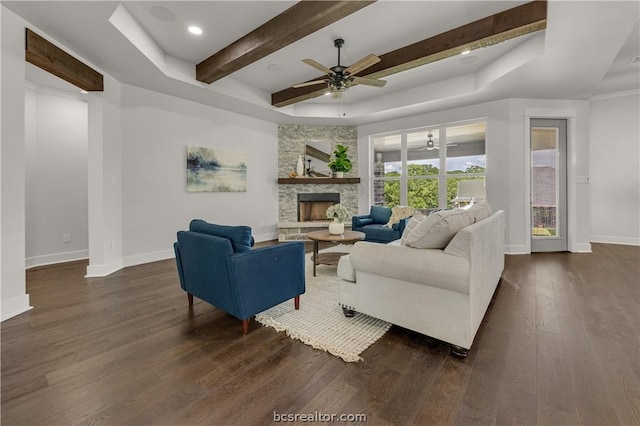 living room featuring a stone fireplace, ceiling fan, beamed ceiling, and dark wood-type flooring