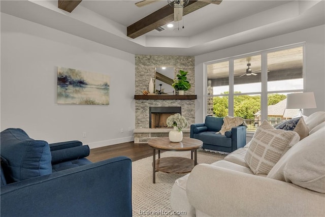 living room featuring a fireplace, hardwood / wood-style floors, a tray ceiling, and ceiling fan