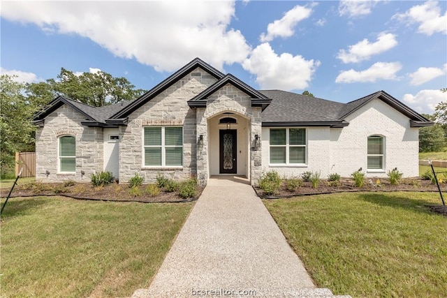 2023 Lola Ln, Bryan, TX 77807 - french country style house with stone siding, a front lawn, and roof with shingles