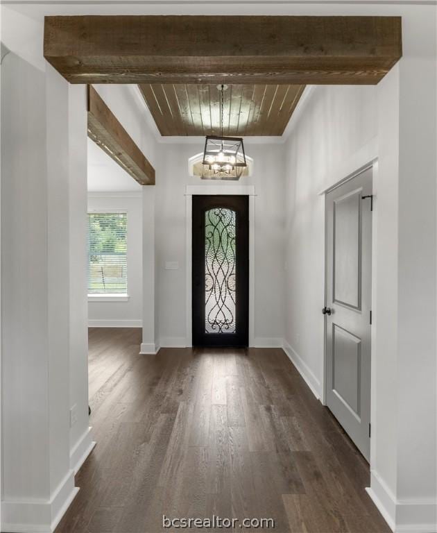 foyer with beamed ceiling, dark wood-type flooring, and an inviting chandelier