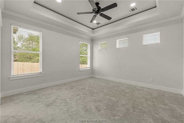 empty room with a tray ceiling, ceiling fan, crown molding, and light colored carpet