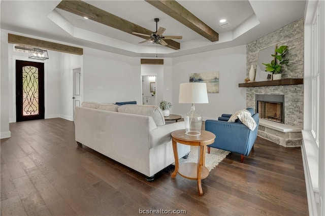 2023 Lola Ln, Bryan, TX 77807 - living room with a raised ceiling, ceiling fan, dark wood-style floors, a stone fireplace, and beamed ceiling