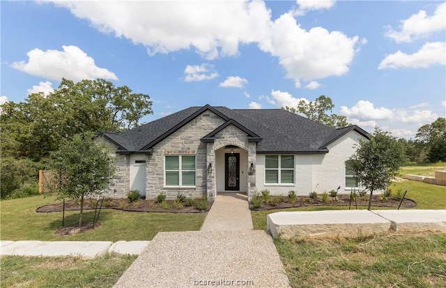 2023 Lola Ln, Bryan, TX 77807 - french country inspired facade featuring stone siding, a front yard, and a shingled roof