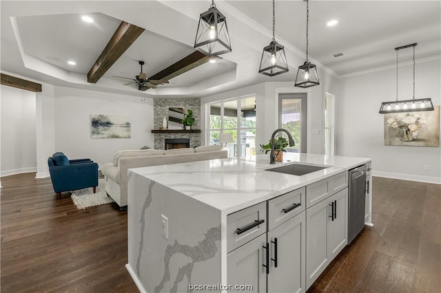 kitchen with dark wood-type flooring, a kitchen island with sink, sink, and pendant lighting