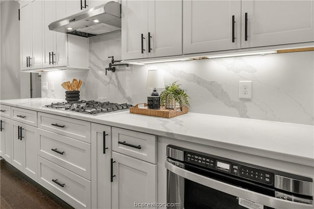 2023 Lola Ln, Bryan, TX 77807 - kitchen featuring under cabinet range hood, stainless steel gas stovetop, white cabinets, oven, and dark wood-type flooring