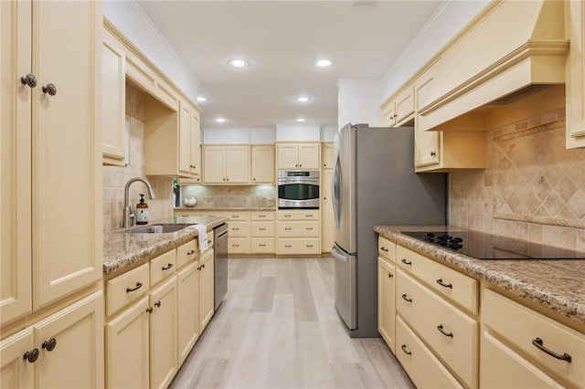 1818 Laura Ln, College Station, TX 77840 - kitchen featuring appliances with stainless steel finishes, decorative backsplash, a sink, cream cabinets, and light wood-style flooring