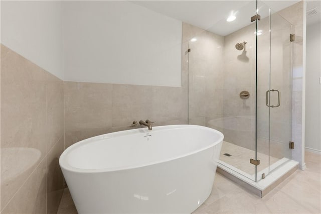 bathroom featuring a shower stall, tile walls, and a freestanding tub