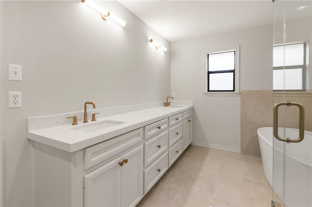 bathroom featuring a sink, a freestanding bath, double vanity, and tile patterned floors