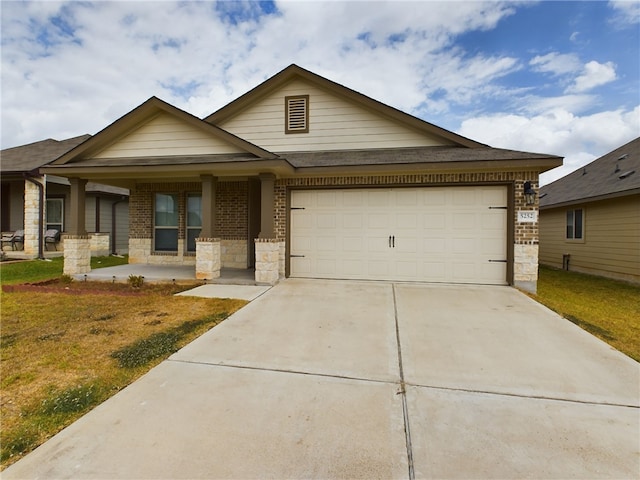 view of front of property featuring covered porch, a garage, and a front yard