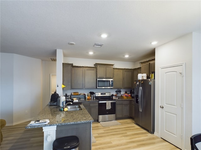 kitchen featuring light hardwood / wood-style floors, kitchen peninsula, sink, and appliances with stainless steel finishes