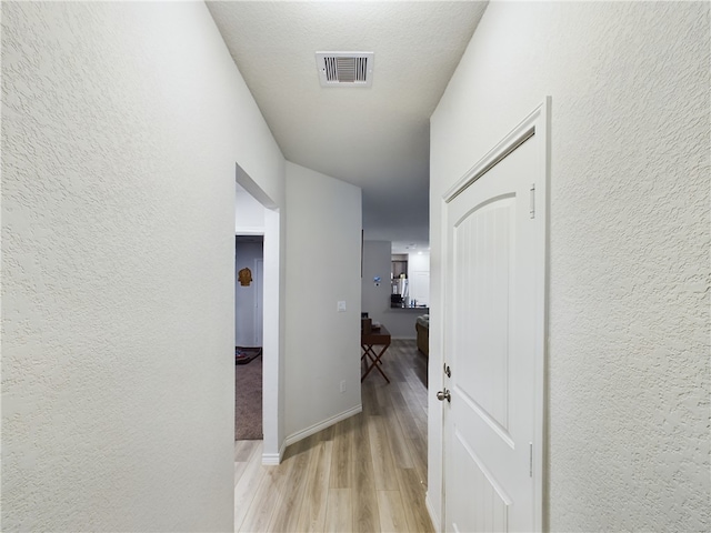 hallway featuring a textured ceiling and light hardwood / wood-style floors