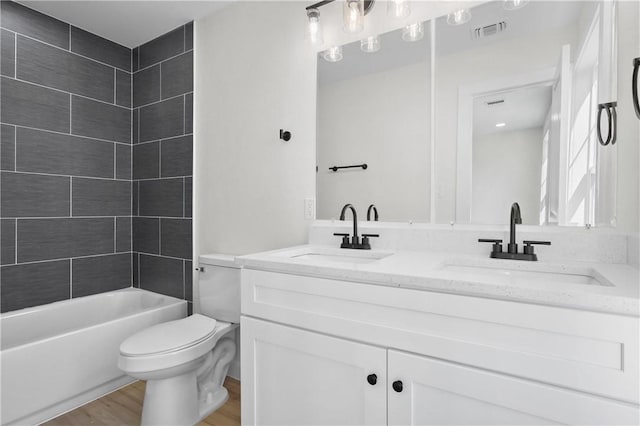 full bathroom featuring hardwood / wood-style floors, vanity, toilet, and tiled shower / bath