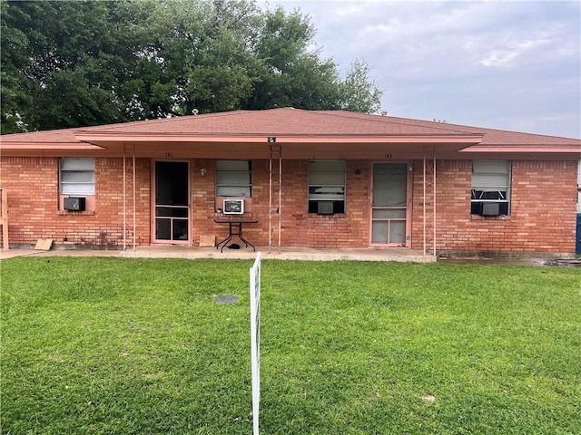 rear view of property featuring a lawn and cooling unit