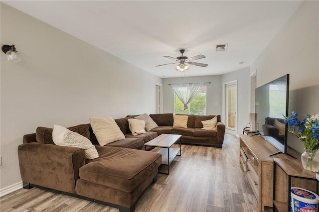 living area with baseboards, a ceiling fan, visible vents, and light wood-style flooring