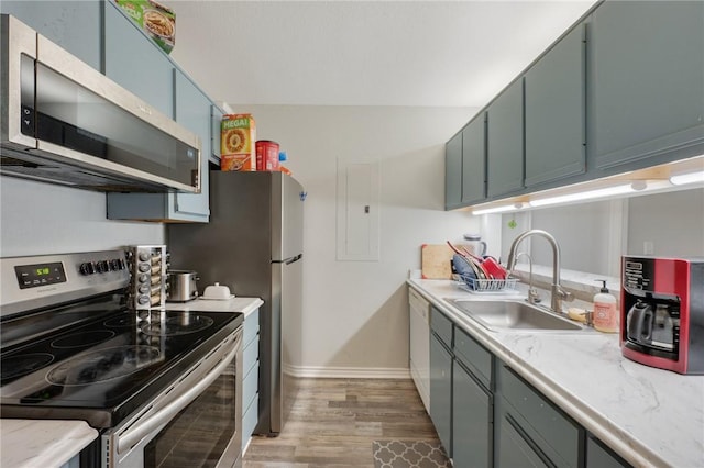 kitchen with a sink, light wood-style floors, stainless steel appliances, light countertops, and baseboards