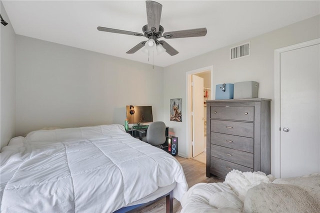 bedroom with light wood-style floors, visible vents, and a ceiling fan
