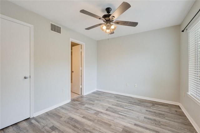 unfurnished bedroom featuring baseboards, multiple windows, light wood-style floors, and visible vents