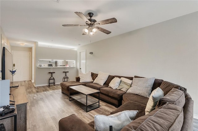 living area with ceiling fan, baseboards, and wood finished floors