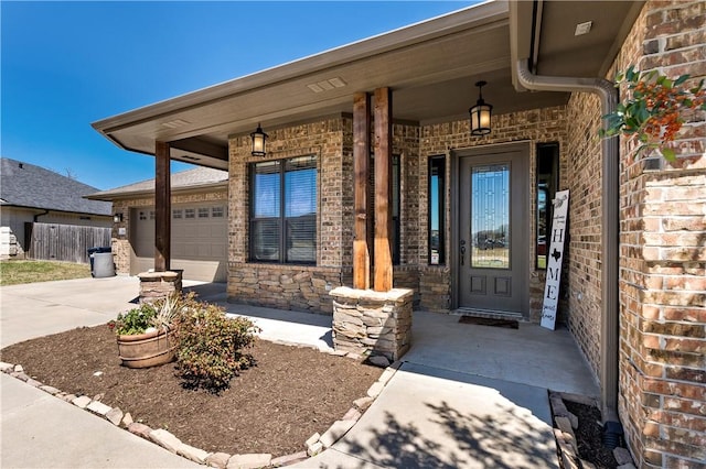 view of exterior entry featuring covered porch, a garage, and driveway