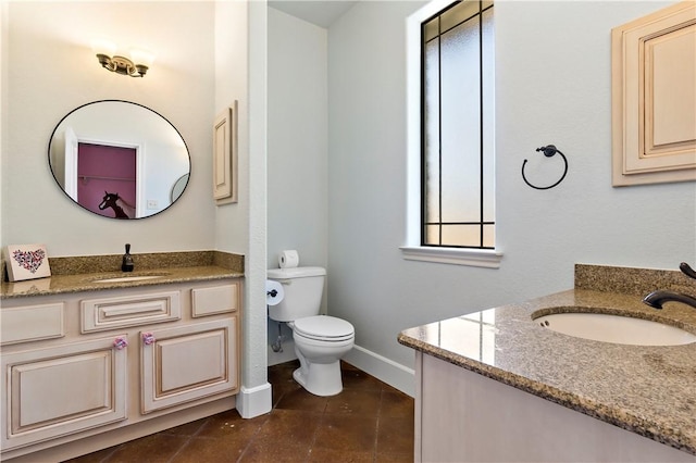 full bath with toilet, tile patterned floors, two vanities, and a sink