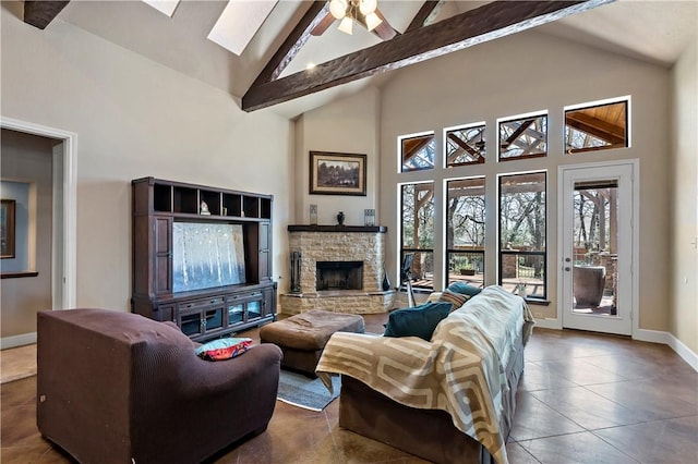 tiled living area with a ceiling fan, baseboards, high vaulted ceiling, beam ceiling, and a stone fireplace