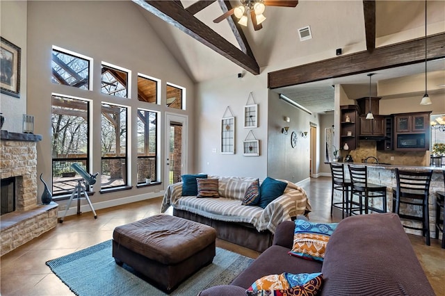 living room featuring high vaulted ceiling, a fireplace, visible vents, and ceiling fan