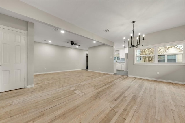 unfurnished living room featuring ceiling fan with notable chandelier and light wood-type flooring