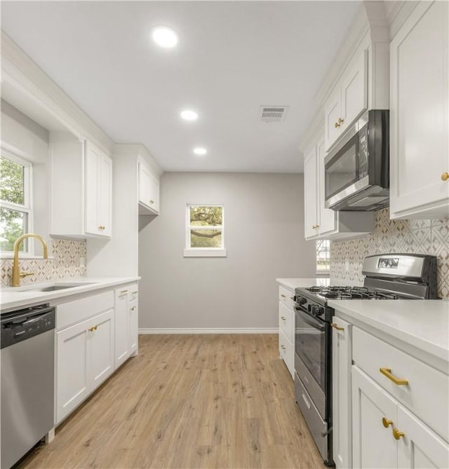 kitchen featuring sink, appliances with stainless steel finishes, plenty of natural light, white cabinets, and light wood-type flooring