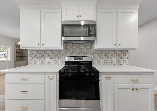 kitchen featuring backsplash, range with gas stovetop, and white cabinets