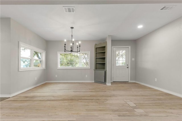 unfurnished dining area featuring an inviting chandelier and light hardwood / wood-style floors