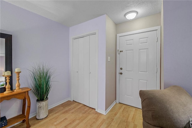 foyer entrance with light hardwood / wood-style floors and a textured ceiling