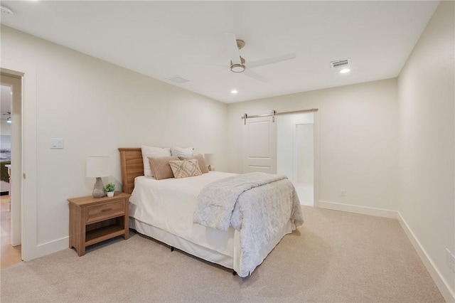 bedroom with light carpet, ceiling fan, and a barn door