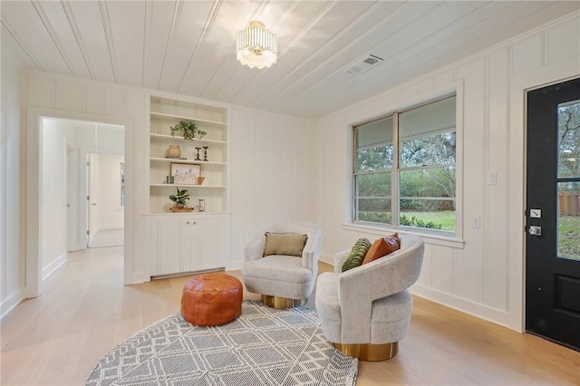 living area with built in shelves, light hardwood / wood-style flooring, wood ceiling, and a notable chandelier