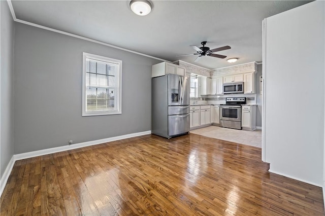 kitchen with light wood-type flooring, ornamental molding, white cabinets, and appliances with stainless steel finishes