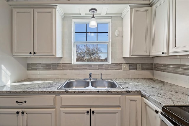 kitchen with light stone counters, decorative backsplash, sink, and hanging light fixtures