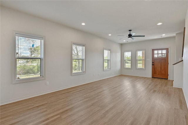 unfurnished living room featuring plenty of natural light, ceiling fan, and light hardwood / wood-style flooring