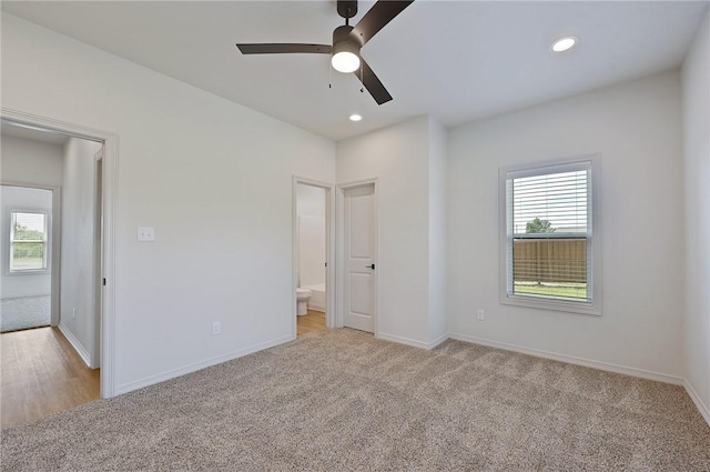 unfurnished bedroom featuring ceiling fan, light colored carpet, and connected bathroom